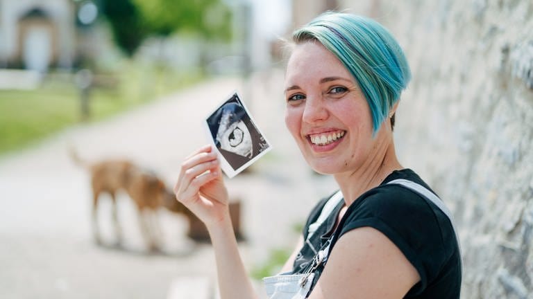 Tanja zeigt lachend ein Ultraschallbild ihres Kindes